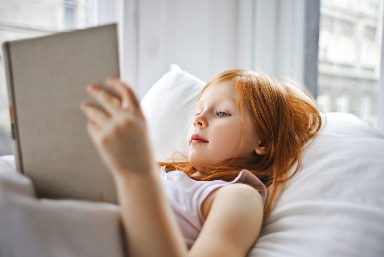 a-girl-reading-a-book-while-lying-on-bed-3761515